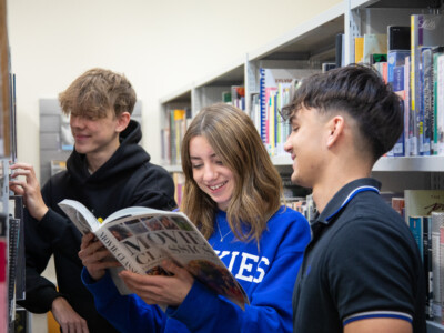 students looking at books in library