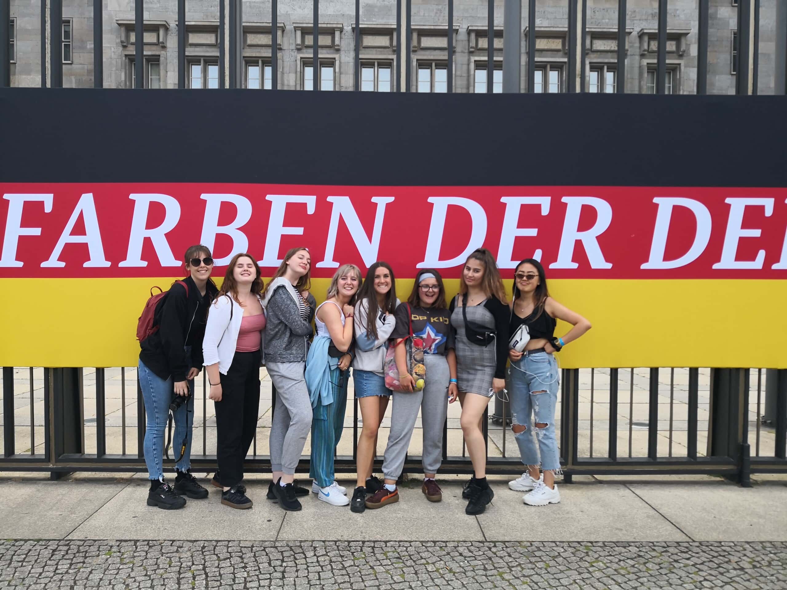 students stand in front of a banner in the colours of the german flag