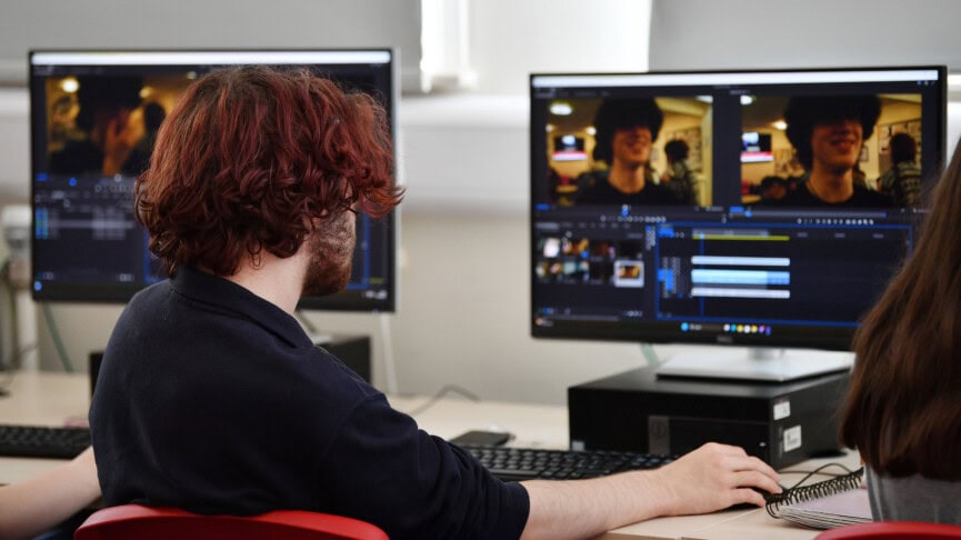 Male student editing a film on a computer