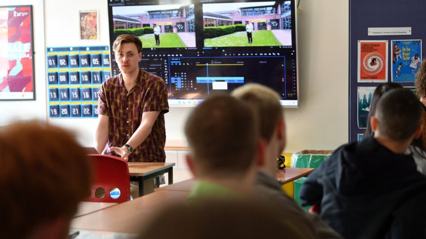 Male film studies teacher addressing students at the front of the classroom