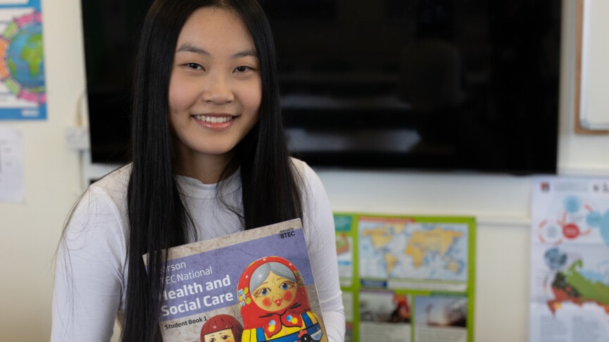 Asian female student holding a health and social care text book