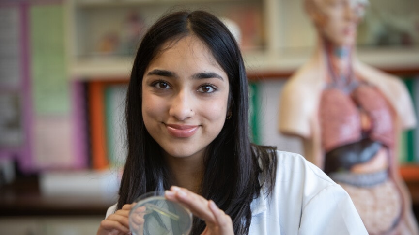 Female Biology student in a white lab coat smiling