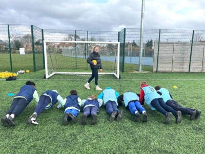 A female student instructing younger students to do push ups on the 3G