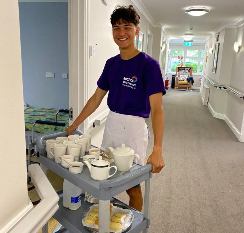 male student delivering tea tray to residents in a care home