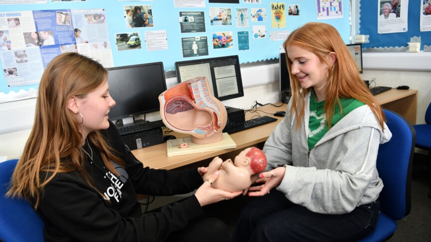 Two Heath & Social care students with a model of a baby in the womb