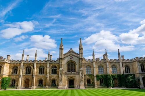 Cambridge university halls with grass in the foreground and blue sky