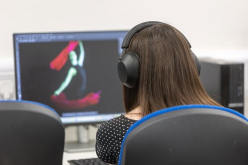 A female student with a headset on working at the computer