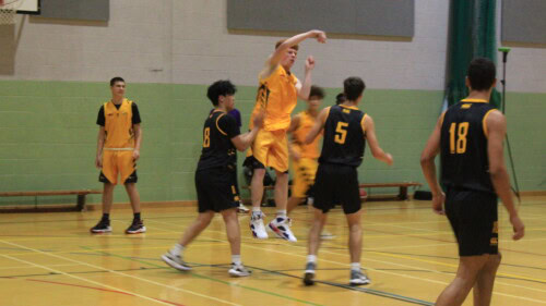 Basketball players on court with a player doing a jump shot