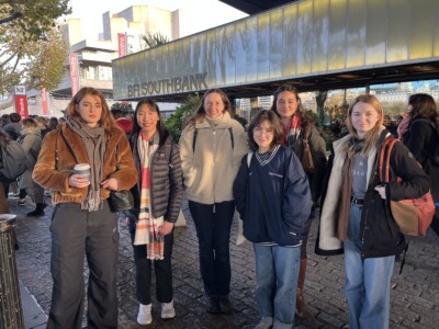 A group of female students with their teacher standing outside BFI Southbank in their coats