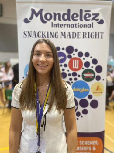 Abbie Sheehan standing next to the Mondelez sign at an Apprenticeship Exhibition