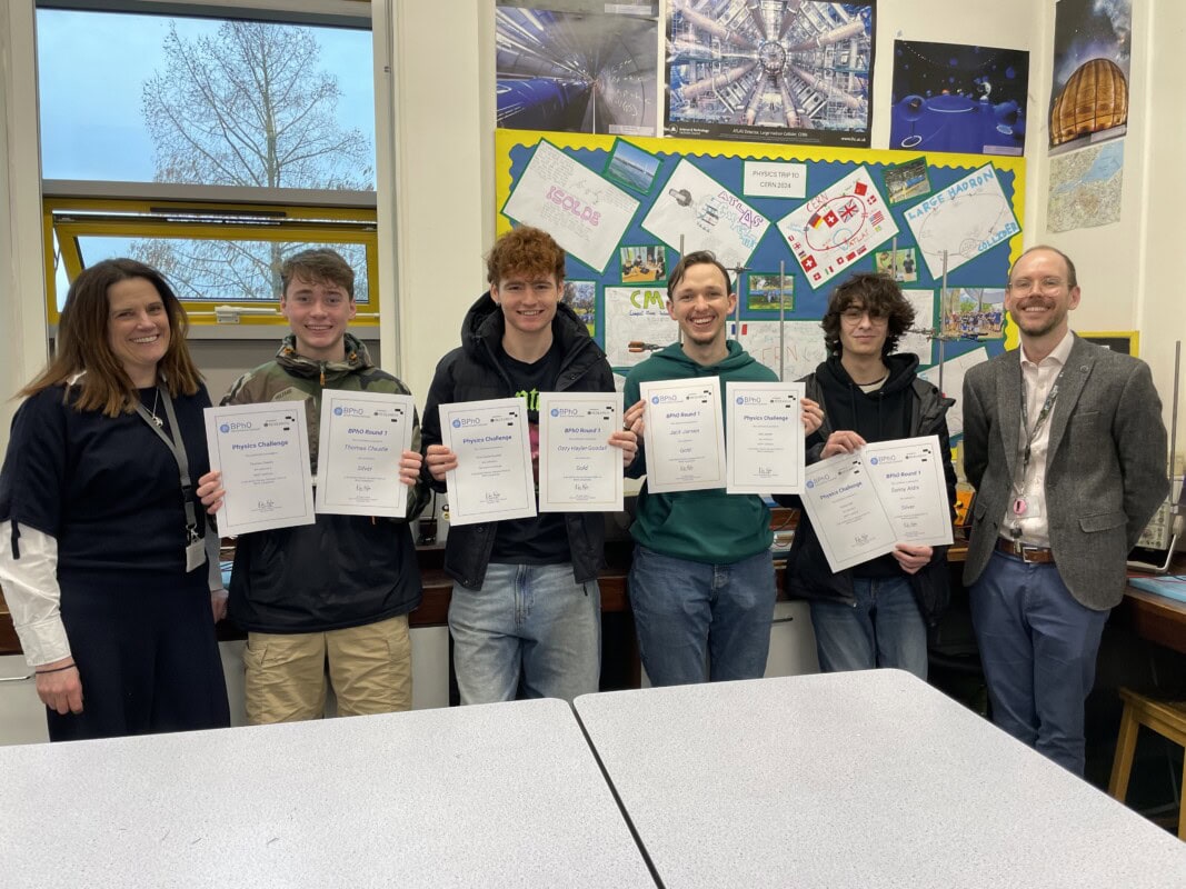 Group of 4 physics students holding certificates with their 2 teachers