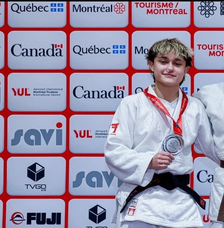 Judo competitor standing on the podium with a silver medal around her neck