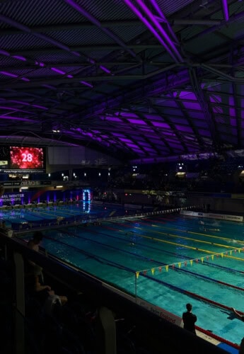 An Olympic pool lit with atmospheric lights