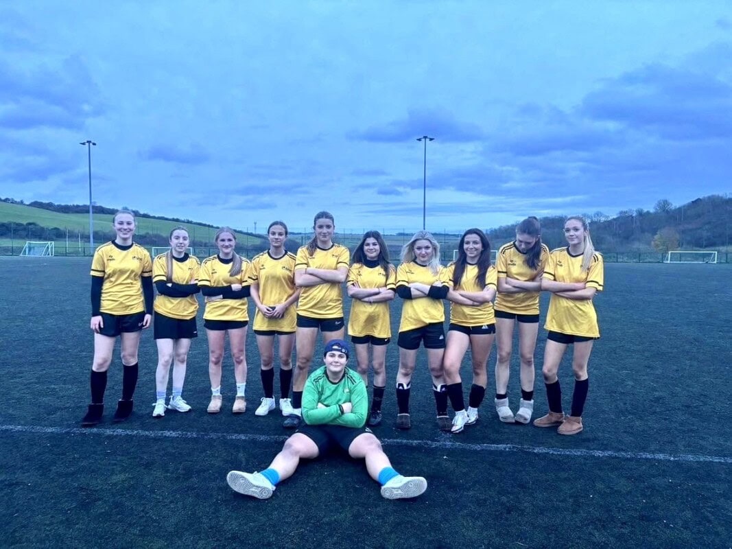 Women's Football Team standing in a row with the goalie sitting in the front