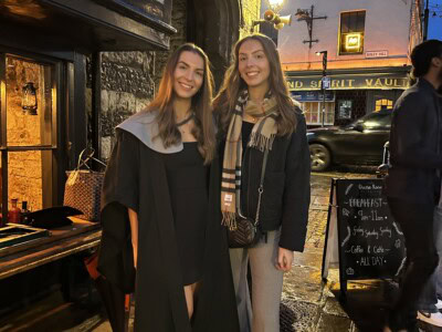 two sisters standing together on a street early evening