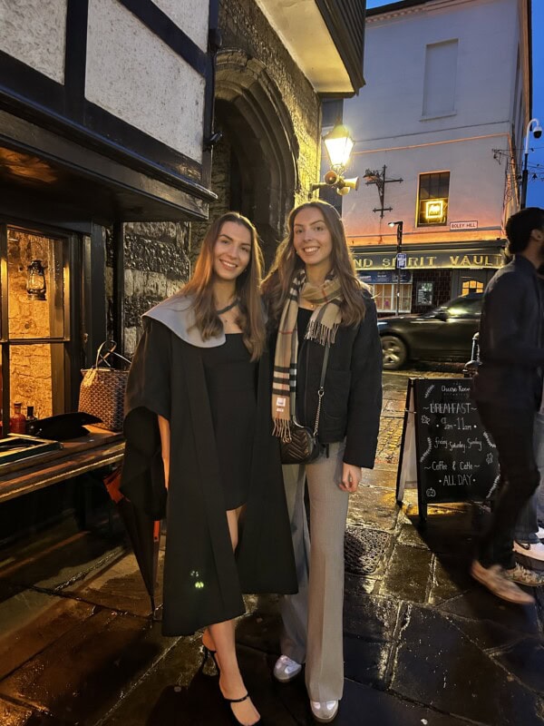 two sisters standing together on a street early evening