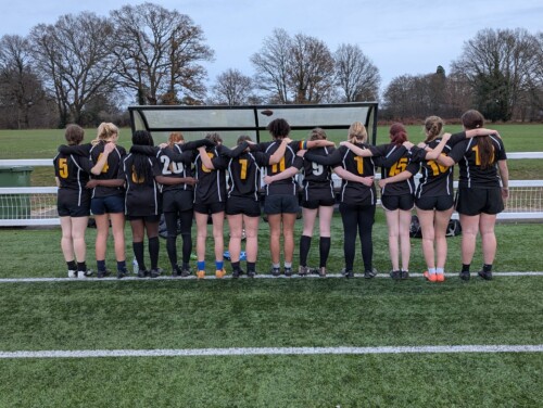 Women's rugby team in a lineup with their backs to the camera