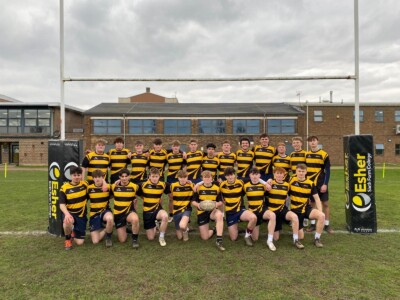 Men's Rugby team posing for a photo under the goal posts