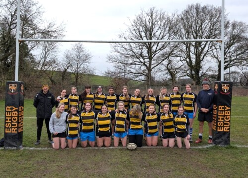 Women's Rugby team posing for a photo underneath the bars