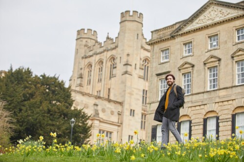 male undergraduate walks past an old building in bristol unviersity