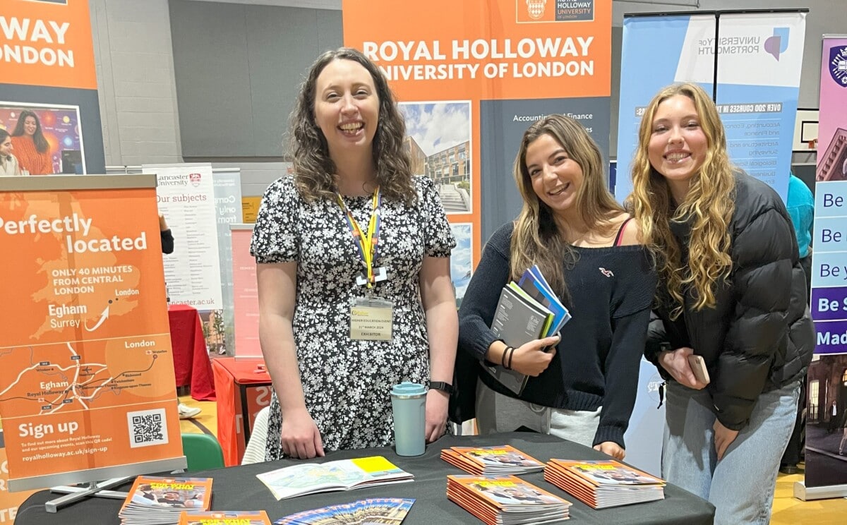 two girls holding prospectuses stand with a university ambassdaor from royal holloway university