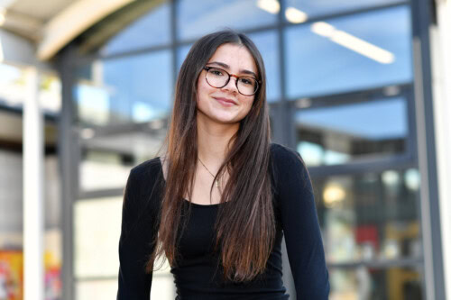 female student wearing glasses poses in a balck top