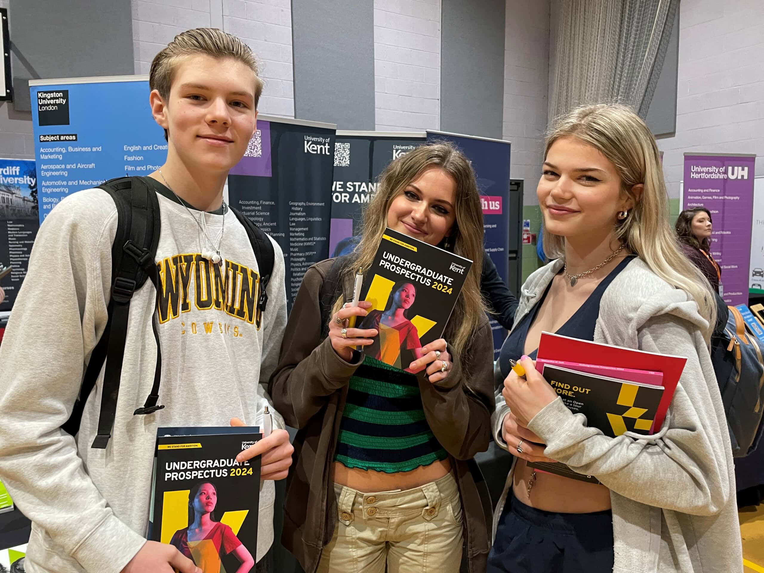 3 student holding university prospectus' they have picked up at HE Day.