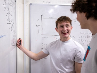 maths student in a white teacher enjoying solving a mathematical problem at the white board
